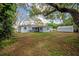 Backyard view of house, featuring green landscaping and a storage shed at 2918 W Ellis Dr, Tampa, FL 33611