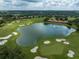 A stunning aerial view showcasing a golf course, a large pond, and surrounding lush greenery at 34714 Heavenly Ln, Dade City, FL 33525