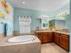 Bathroom featuring a garden tub, wood cabinets with granite countertops, and large mirrors at 34714 Heavenly Ln, Dade City, FL 33525