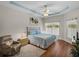 Bedroom with tray ceiling, fan, wood floors, patterned comforter, recliner and view of the backyard at 34714 Heavenly Ln, Dade City, FL 33525