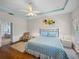 Bedroom featuring hardwood floors, blue patterned comforter, tray ceiling, and ensuite bath access at 34714 Heavenly Ln, Dade City, FL 33525