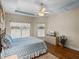 Bedroom with tray ceiling, ceiling fan, wood floors, and view of backyard through multiple windows at 34714 Heavenly Ln, Dade City, FL 33525