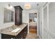 Bathroom featuring dual sinks with granite countertops, dark wood cabinets, and a walk-in door to a bedroom at 39650 Us Highway 19 N # 1422, Tarpon Springs, FL 34689