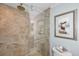 Bathroom with glass shower, tiled walls, a stone floor, and a unique piece of artwork hanging on the wall at 39650 Us Highway 19 N # 1422, Tarpon Springs, FL 34689