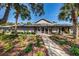 Community clubhouse entrance surrounded by lush landscaping and a well-maintained sidewalk at 39650 Us Highway 19 N # 1422, Tarpon Springs, FL 34689