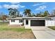 Charming single-story home featuring a modern black garage door, freshly painted white facade and a well-manicured front lawn at 4118 Ramona Dr, Spring Hill, FL 34606