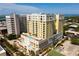 Beautiful aerial view of yellow multi-story condo building with an outdoor pool and tropical landscaping at 628 Cleveland St # 1507, Clearwater, FL 33755
