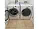 Bright laundry area with white front-loading washer and dryer set and tile floor at 628 Cleveland St # 1507, Clearwater, FL 33755
