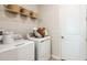A functional laundry room features a washer and dryer and has decorative baskets on a shelf for storage at 746 Steel Dr, Apollo Beach, FL 33572