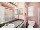 A full bathroom with modern vanity, shower, toilet, and bright pink walls, offers style and functionality at 7501 Hollowell Dr, Tampa, FL 33615