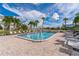 Community pool area with lounge chairs on a brick deck with palm trees on a bright day with blue skies at 7560 Bay Island S Dr # 144, South Pasadena, FL 33707