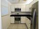Galley kitchen boasting stainless steel appliances, granite counters, bright white cabinets, and tile flooring at 7560 Bay Island S Dr # 144, South Pasadena, FL 33707