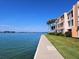 Beautiful waterfront building with a concrete path alongside lush green grass and beautiful palm trees on a bright sunny day at 7560 Bay Island S Dr # 144, South Pasadena, FL 33707