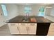 Kitchen island featuring a stainless sink, ample storage, granite counters, and black dishwasher at 10908 Carlton Fields Dr, Riverview, FL 33579