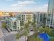 Wide aerial view of condo with balconies, palm trees, street-level shops, blue sky, and water in the background at 111 N 12Th St # 1819, Tampa, FL 33602