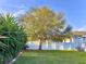 Well-maintained backyard with a large tree, lush lawn, and white fence at 11566 Balintore Dr, Riverview, FL 33579