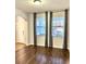 Living room featuring hardwood floors, two large windows with decorative gray curtains, and an arched doorway at 11566 Balintore Dr, Riverview, FL 33579