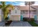 Townhouse exterior with a garage, blue door, and palm trees at 12308 Sun Vista W Ct # 45, Treasure Island, FL 33706