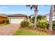 Charming single-story home with lush tropical landscaping, a paved driveway, and a two-car garage at 15644 Aurora Lake Cir, Wimauma, FL 33598