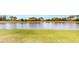 Scenic view of the tranquil lake from the well-maintained lawn, lush green grass, and trees at 15644 Aurora Lake Cir, Wimauma, FL 33598