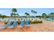 Community pool area with blue lounge chairs, palm trees, and a covered seating area at 15644 Aurora Lake Cir, Wimauma, FL 33598