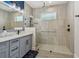 Contemporary bathroom with gray cabinets, marble countertop, framed mirror, and step-in shower at 17441 Savory Mist Cir, Bradenton, FL 34211