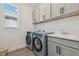 Bright laundry room with modern washer and dryer, sink, and white cabinets at 17441 Savory Mist Cir, Bradenton, FL 34211