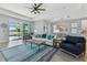 Bright living room with stylish furniture, ceiling fan, and sliding glass doors leading to outdoor pool and lake view at 17441 Savory Mist Cir, Bradenton, FL 34211
