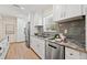 Updated kitchen featuring gray backsplash, granite counters, stainless steel appliances, and white cabinets at 3600 Locust Ne St, St Petersburg, FL 33704