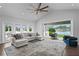 Open living room featuring large windows, modern fan, and sliding doors to screened patio with water view at 370 Coffee Pot Riviera Ne, St Petersburg, FL 33704