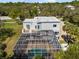 Aerial view of a white home with a large screened-in pool area amidst lush greenery at 375 Wellington Ave, Oldsmar, FL 34677