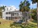 Rear exterior view of a house featuring a screened in patio, tall palm trees, and luscious green grass at 375 Wellington Ave, Oldsmar, FL 34677