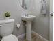 Cozy half bathroom with a pedestal sink, toilet, and decorative mirror at 4272 Cloud Hopper Way, Lutz, FL 33559