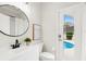 Bright bathroom with white cabinets, round mirror, and a view of the pool through the glass door at 434 Arch Ridge Loop, Seffner, FL 33584