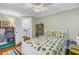 Bedroom with bug-themed bedding, a ceiling fan, and a view into the hallway with staircase beyond at 436 12Th Ne Ave, St Petersburg, FL 33701
