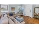 Living room with wood floors, a large sofa, two windows and a TV on a white TV stand at 436 12Th Ne Ave, St Petersburg, FL 33701