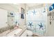 Bathroom with granite countertop sink and starfish themed decorations on the walls and shower curtain at 4607 Ballantrae Boulevard, Land O Lakes, FL 34638