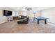 Large carpeted living room with brown sectional couch, ping pong table, tv, and windows providing natural light at 4607 Ballantrae Boulevard, Land O Lakes, FL 34638