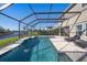 Inviting pool area with screened enclosure and travertine deck overlooking a serene lake at 4607 Ballantrae Boulevard, Land O Lakes, FL 34638