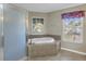 Bright bathroom showcasing a tiled whirlpool tub, a glass shower, and a window with natural light at 4804 Patagonia Pl, Land O Lakes, FL 34638