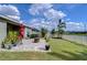 Landscaped backyard featuring a stone patio with a fire pit, green lawn, and views of the pond at 11605 Cleyera Ct, Riverview, FL 33579