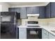 Galley kitchen with painted cabinets, light countertops, and black appliances at 11706 Raintree Village Blvd # D, Temple Terrace, FL 33617