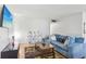 Bright living room features laminate flooring, a blue sofa, decorative shelving, and a wall-mounted television at 11706 Raintree Village Blvd # D, Temple Terrace, FL 33617