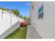Narrow side yard with fresh lawn and a white fence with a cozy red bench at 1214 Windsor Cir, Brandon, FL 33510