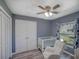 This bedroom is set up with a crib, rocker, and ceiling fan, plus a large closet and beautiful natural light at 2988 Pinewood Run, Palm Harbor, FL 34684