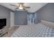 Cozy main bedroom with gray walls, ceiling fan, neutral decor, and attached bath at 2988 Pinewood Run, Palm Harbor, FL 34684