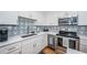 Bright kitchen featuring stainless steel appliances, stylish backsplash, and white cabinetry at 420 64Th Ave # 907, St Pete Beach, FL 33706