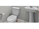 Small bathroom with toilet and pedestal sink with chrome fixtures at 4212 Cloud Hopper Way, Lutz, FL 33559