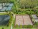 Aerial view of basketball and tennis courts plus a pond with lush greenery in this community at 4849 Isola Ct, Wesley Chapel, FL 33543