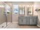 Modern bathroom with double vanity, granite countertops, walk-in shower, and stylish gray tiling at 4849 Isola Ct, Wesley Chapel, FL 33543